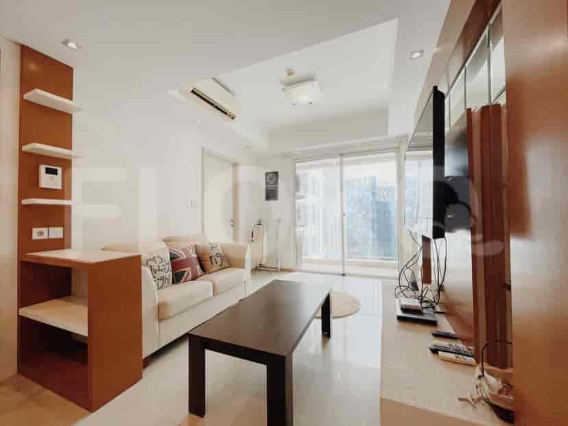 Ruang tamu dengan sofa, TV, dan pemandangan balkon.