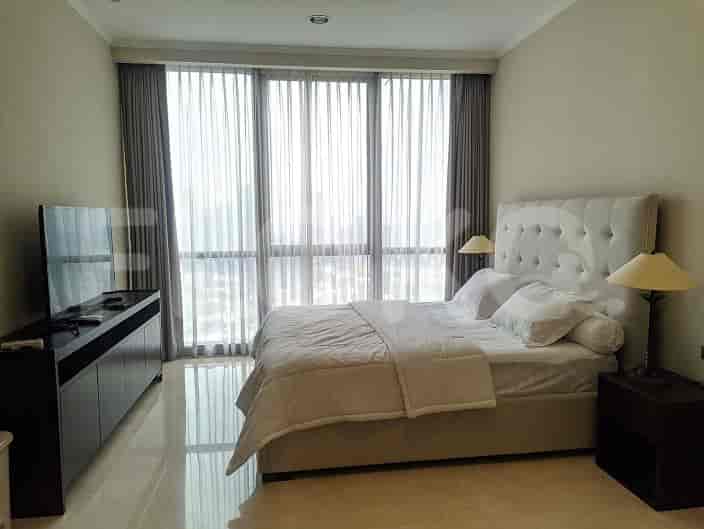 A bright bedroom showcasing a large bed, a TV, and large windows.