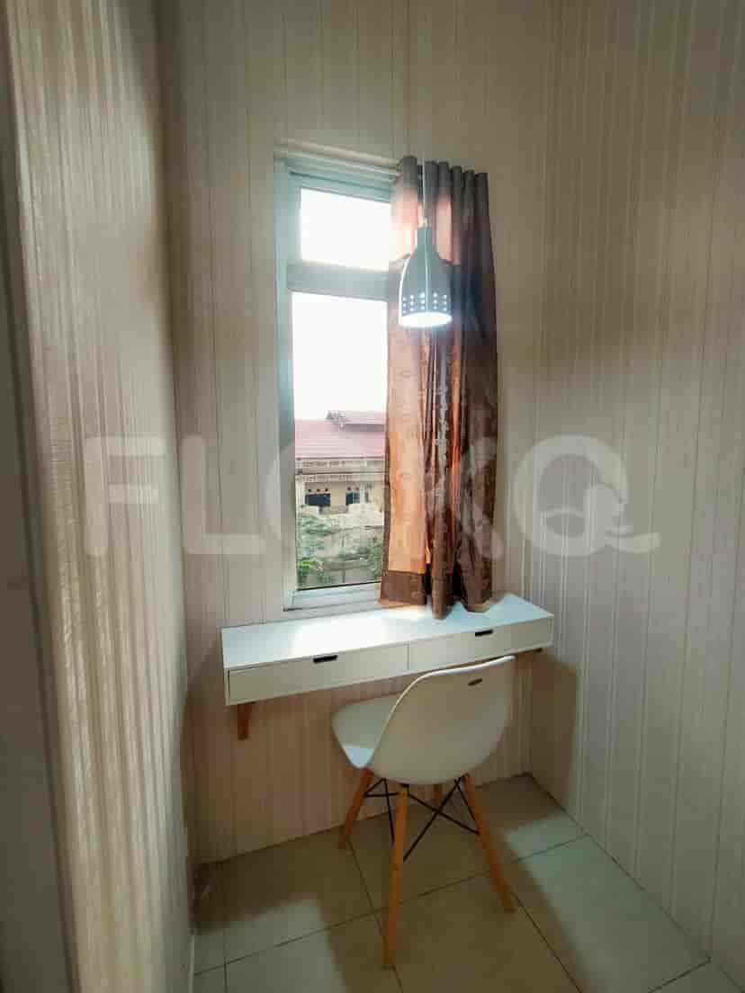 A small study nook by a window, featuring a desk, chair, and a pendant lamp.