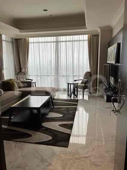 A spacious living room featuring a large L-shaped sofa, smart TV, and a dining area visible in the background.