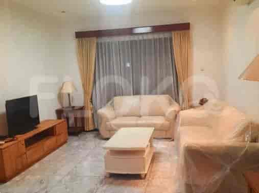 Ruang tamu dengan sofa, TV, dan jendela dengan gorden.