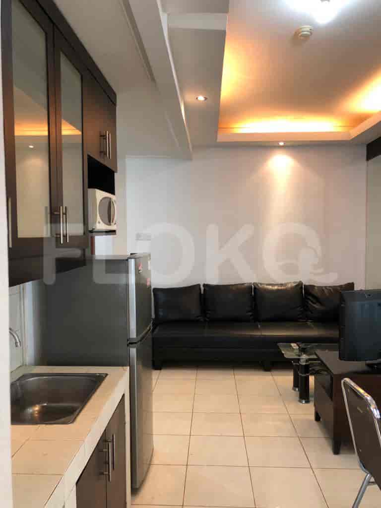A view encompassing both the kitchen and living room, showing the sofa, dining table, and kitchen appliances.