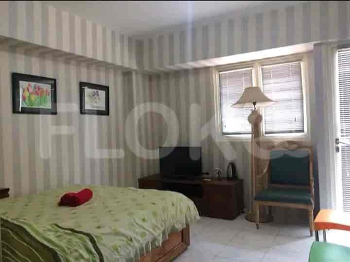 A bedroom with a striped wall, a double bed, a floor lamp, and a TV.