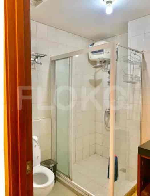 Bathroom featuring a shower, a toilet, and white tiles.
