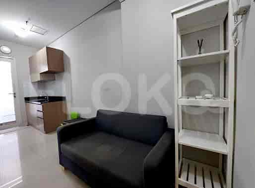 A studio apartment with a small kitchen, sofa, and shelving unit.