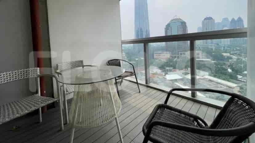 A balcony with a view of the city, a table and chairs.