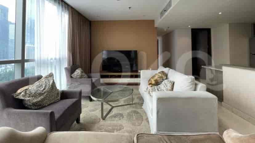 Living room featuring a smart TV on the wall, a grey sofa, and a glass table.