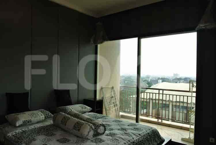 A bedroom featuring a large bed with patterned bedding, a balcony, and cityscape view.