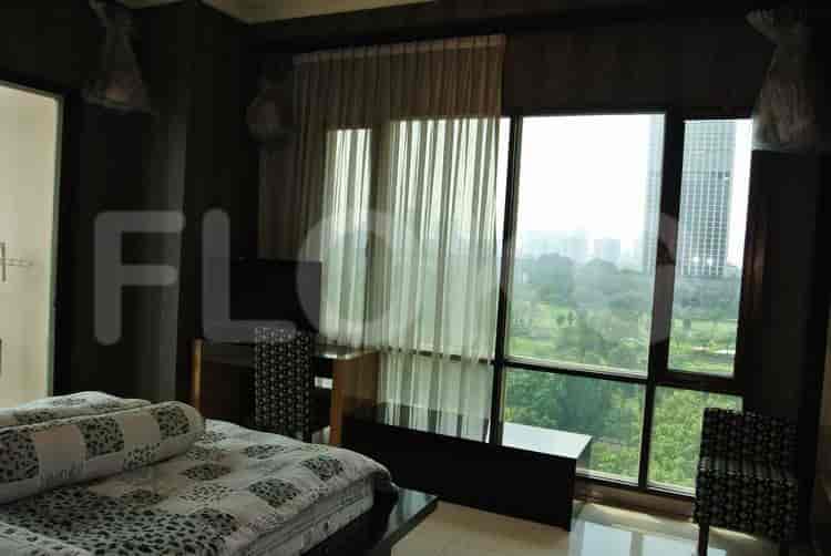 Bedroom with large windows offering a city view, a desk, and a chair.