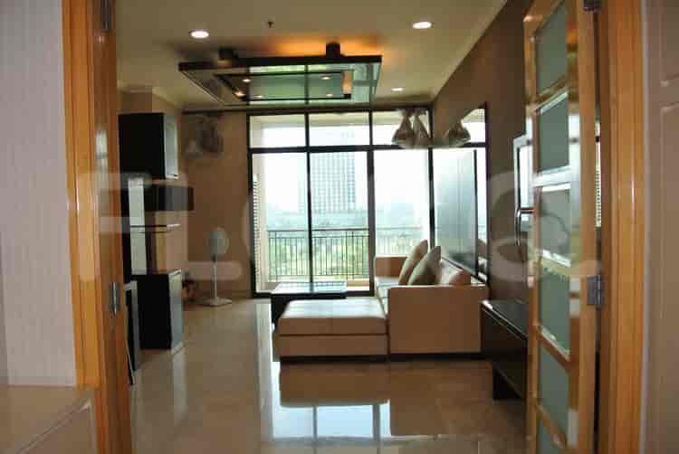 A spacious living room with a beige sectional sofa, dark wood built-ins, and a large window overlooking a cityscape.