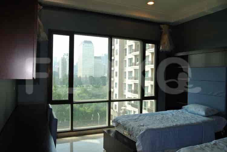 Twin beds in a bedroom with large windows and city views.