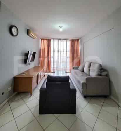 A living room with a grey sofa, wooden entertainment unit, TV, and clock.