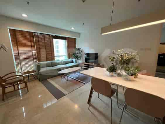 A well-lit living room featuring a sectional sofa, dining area, and large window with blinds.