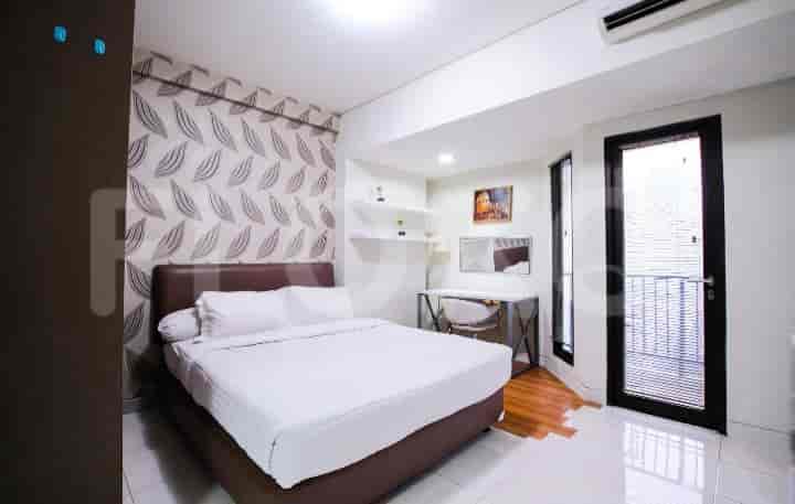 A well-lit bedroom featuring a double bed, work desk, and balcony access.