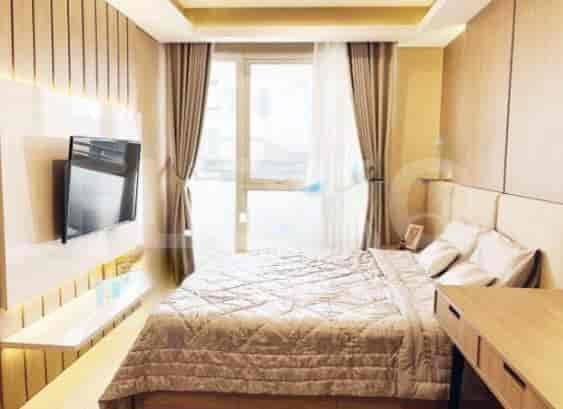 A bedroom with a bed, a smart TV, and wooden paneling.