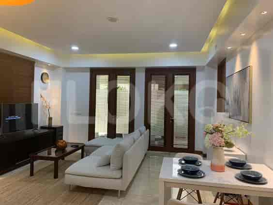 A living room with a grey sofa, entertainment unit, and a view of an outdoor space.