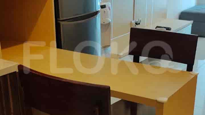 The dining or working area has a desk and two chairs with a kitchen partially visible.