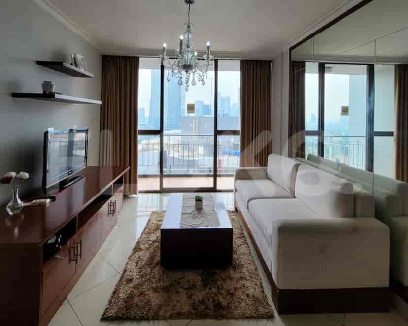 A living room with a white sofa, a coffee table, and a view of the city.