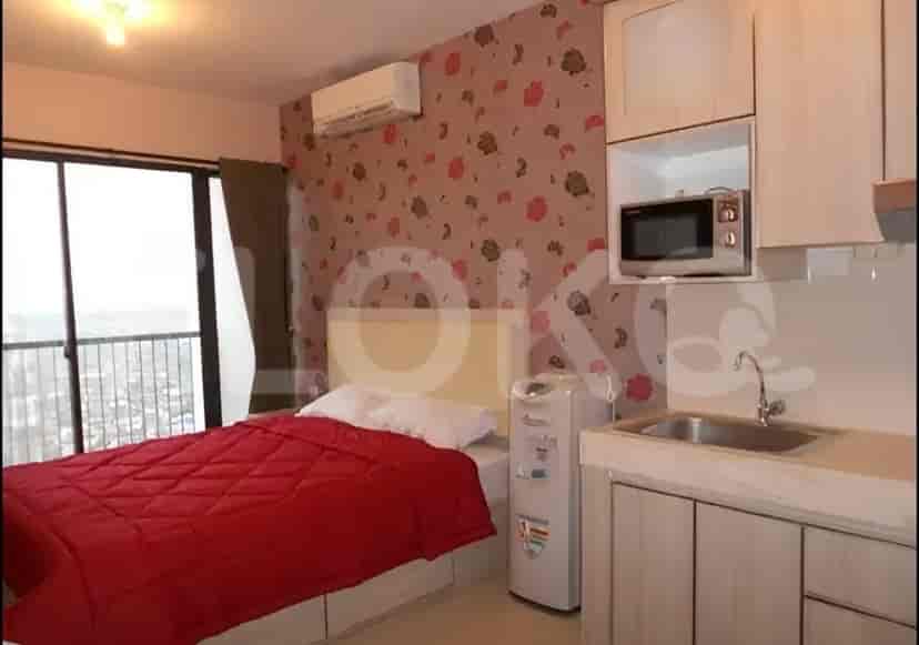 A studio apartment bedroom with a bed, floral wallpaper, and a view from the window.