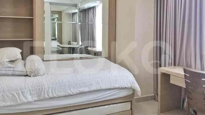 A bedroom with a bed, large mirror, and desk.