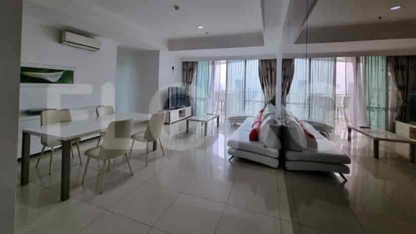 A spacious living room with a white sofa, dining table, and balcony access.