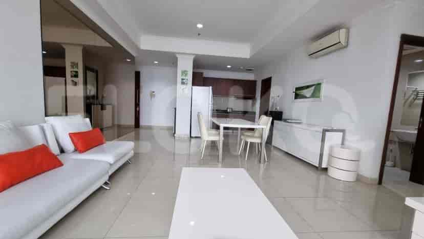 A bright living room with a white sofa, dining area, and access to the kitchen.