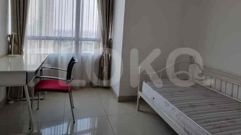 A bedroom with a single bed, desk, and a large window with curtains.