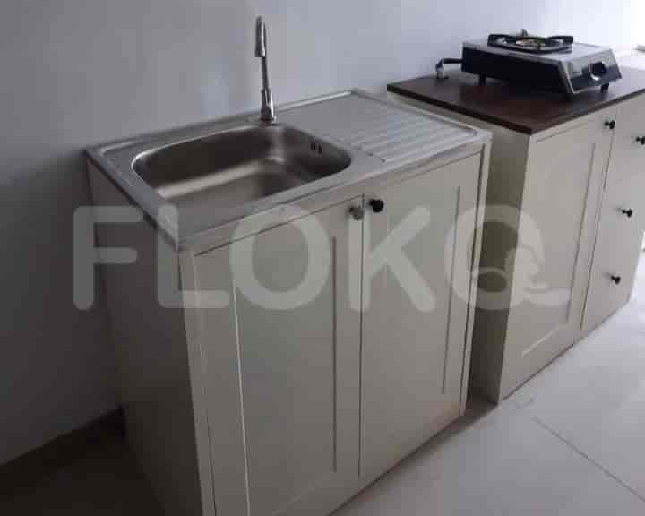 Close up view of kitchenette, showing the sink and a stove top.