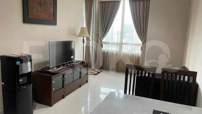 A well-lit living room with a TV, water dispenser, and dining table.