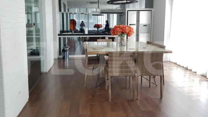 The dining area with a large glass table, wicker chairs, and a view into the kitchen.