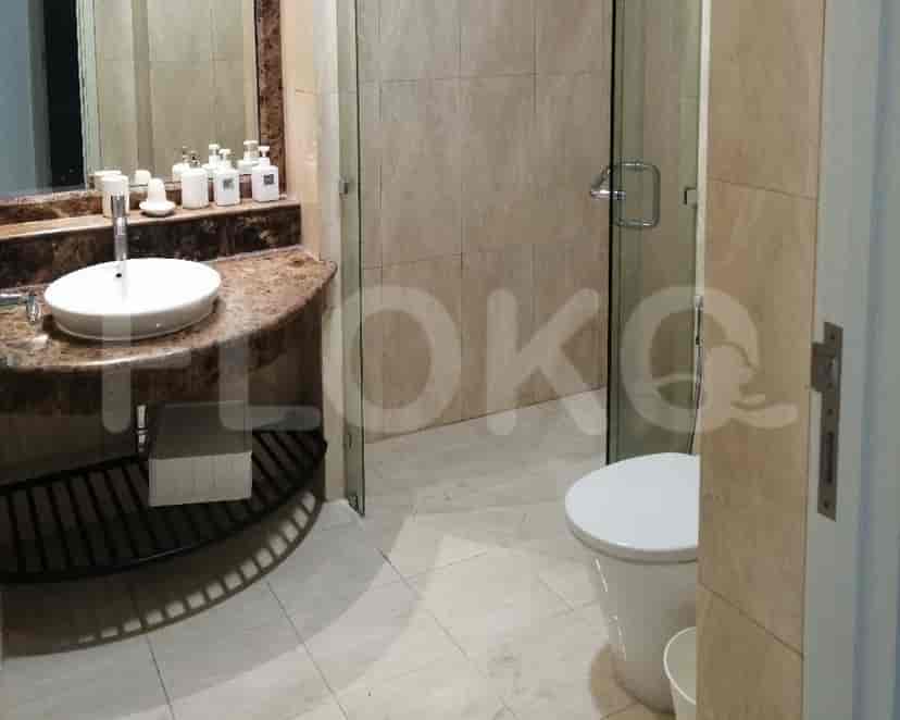 A modern bathroom with a marble sink, toilet, and a glass door.