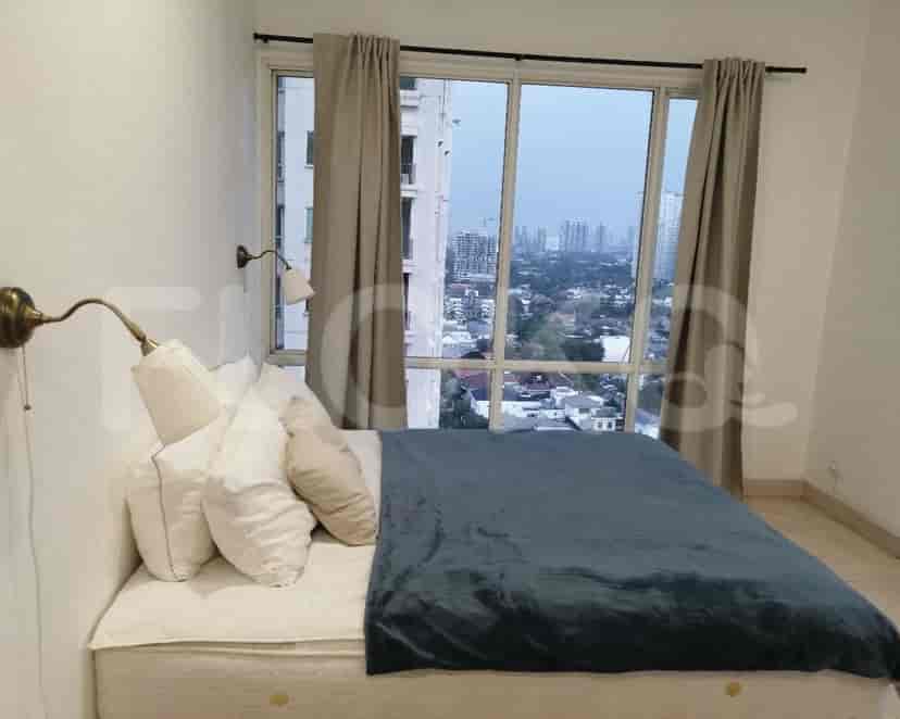 A bedroom with a queen bed, wall lights, and large windows overlooking the city.