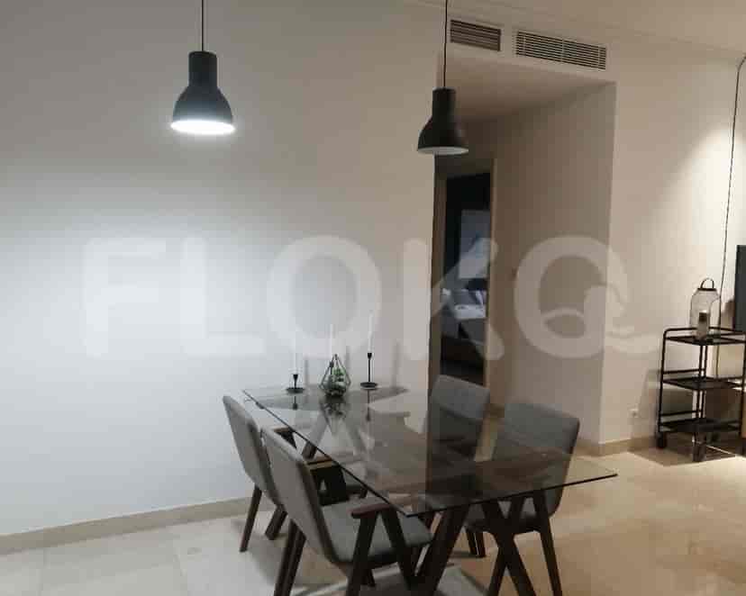 A minimalist dining room with a glass table, chairs, and pendant lights.