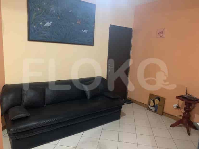 A living room featuring a black sofa, artwork, and a door.