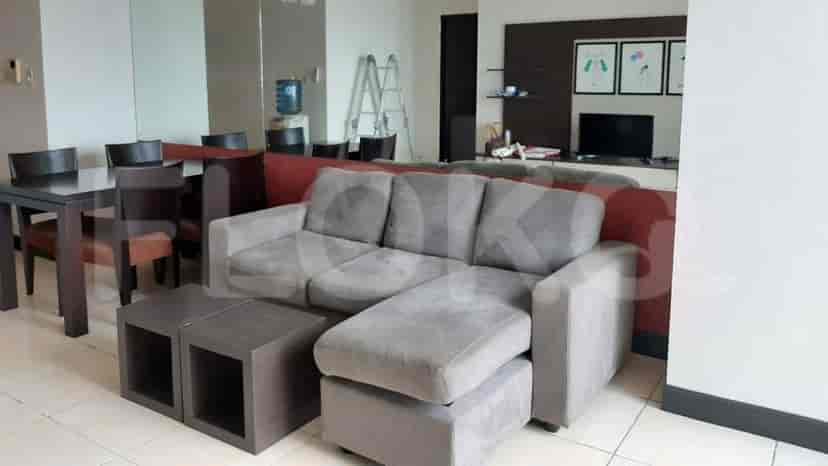 Living room featuring a sofa, entertainment unit with artwork, and door to the bedroom.