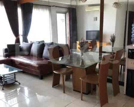 A living room with a brown leather sofa, glass top coffee table, and dining area in the background.