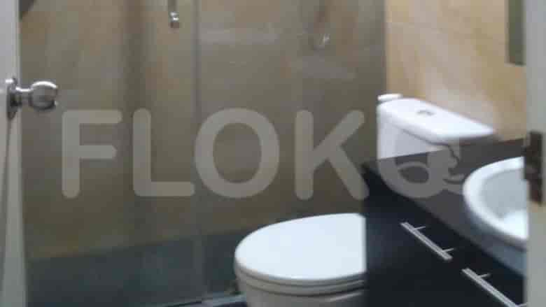 Modern bathroom setup with a toilet, sink, and glass shower door.
