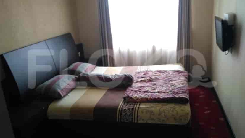 Bedroom featuring a bed, bedside tables, and a wall-mounted TV.