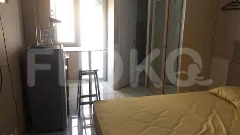 A small studio apartment with a bed, kitchenette, and bathroom.