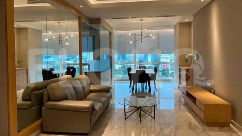A modern living room with a tan sofa, glass coffee table, and a view of the city.