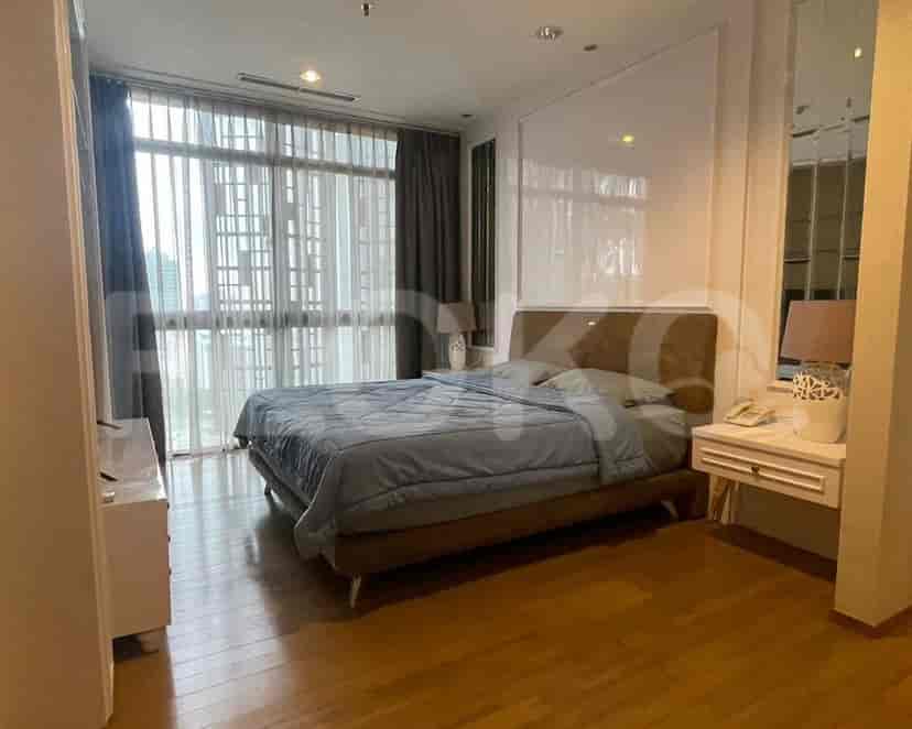 A bedroom with a large bed, bedside tables, and windows.
