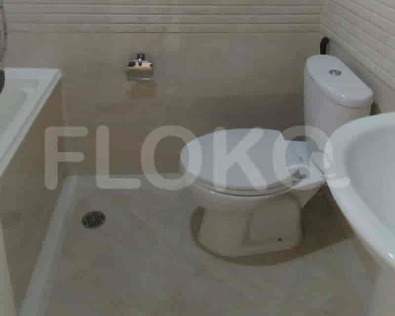 A bathroom with a toilet, a sink, and light-colored tiles.