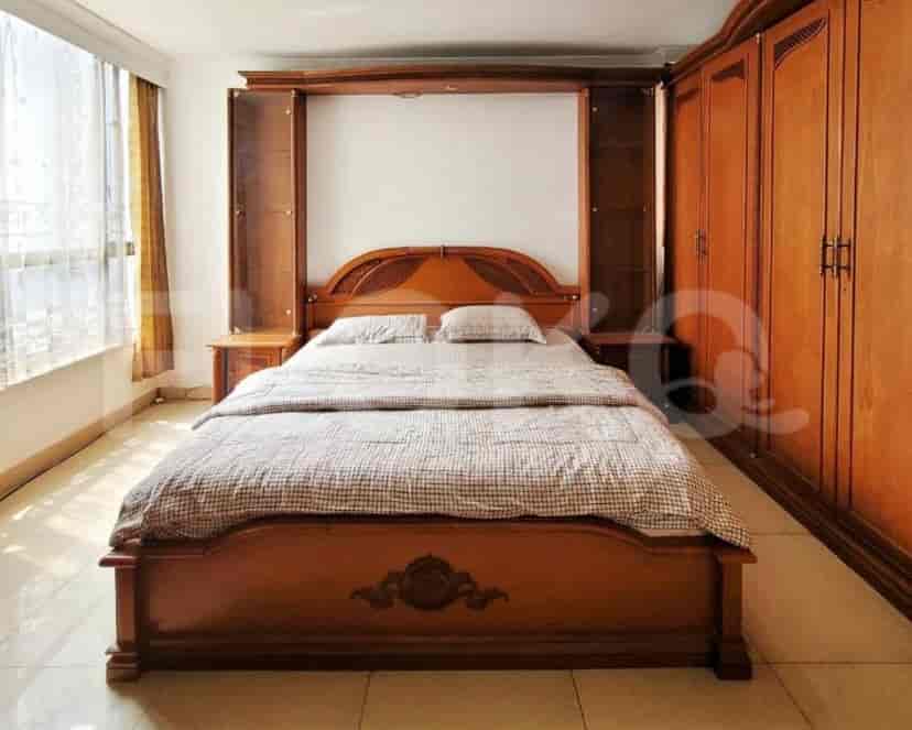 Bedroom with a large wooden bed, built-in wardrobes, and a window with curtains.