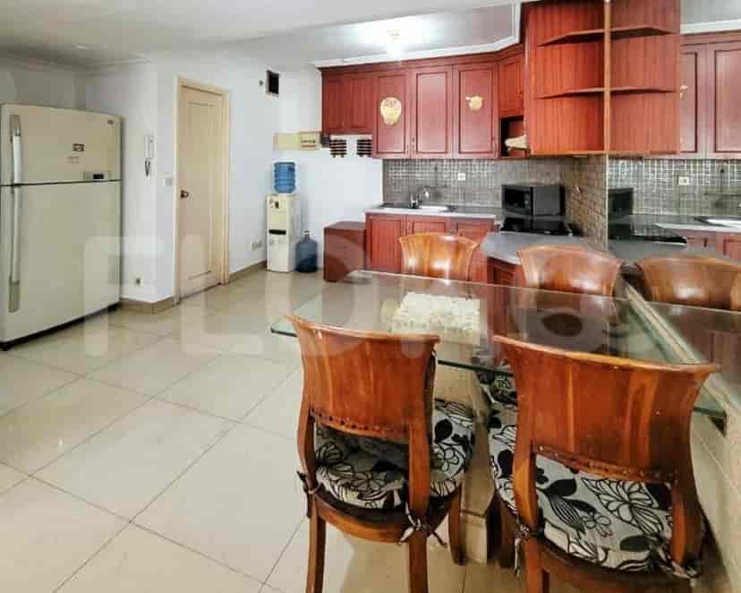 Kitchen and dining area with wooden cabinets, glass-top table, and tiled floor.