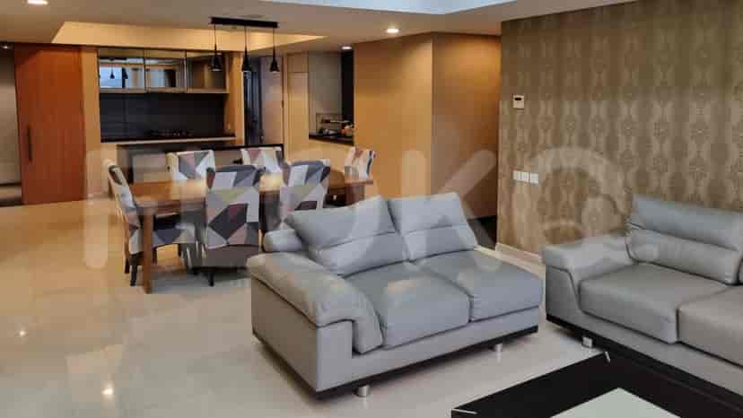 Spacious living and dining area with grey leather sofas, a wooden dining table with patterned chairs, and a kitchen in the background.