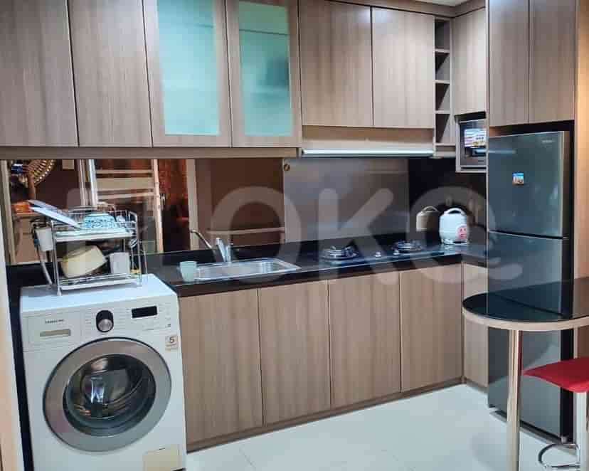 A modern kitchen with wooden cabinets, a washing machine, and a dining table.