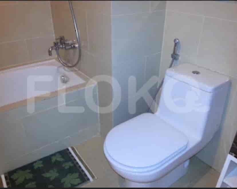 A minimalist bathroom with a bathtub, toilet, and tiled walls.
