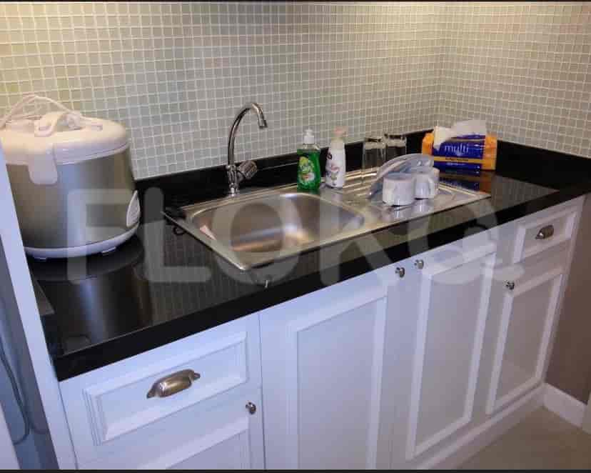 A well-equipped kitchen with a black countertop, stainless steel sink, and white cabinets.