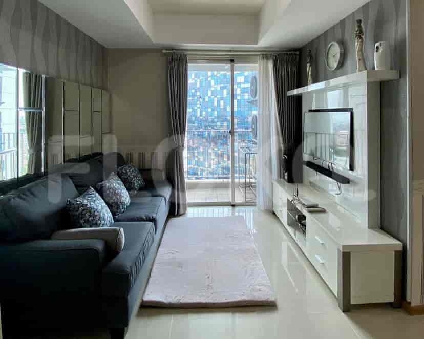 Modern living room with grey sofa, TV, and a city view.