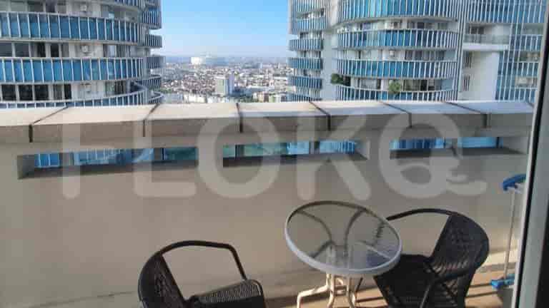 A balcony with a table and chairs, offering a view of surrounding buildings.